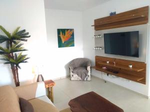 a living room with a flat screen tv on a wall at APTo 300MTS DA PRAIA, VISTA PARA O MAR, CHURRASQUEIRA, WI-FI, AR CONDICIONADO, TOTALMENTE EQUIPADO in Ubatuba