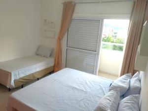 a bedroom with two twin beds and a window at APTo 300MTS DA PRAIA, VISTA PARA O MAR, CHURRASQUEIRA, WI-FI, AR CONDICIONADO, TOTALMENTE EQUIPADO in Ubatuba +47 photos