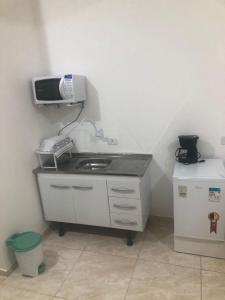 uma cozinha com um lavatório e um telefone na parede em Pousada Tropical no Guarujá