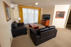 a living room with two leather chairs and a television at Springwood Tower Apartment Hotel in Springwood