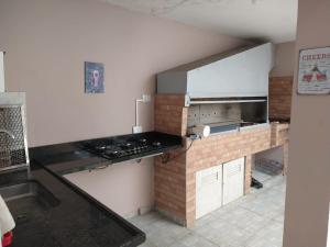 a kitchen with a stove and a brick wall at Peruíbe Centro - P&R in Peruíbe