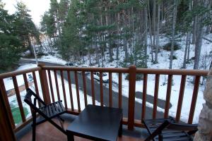 un balcón con 2 sillas, una mesa y un bosque cubierto de nieve en Apartamento Supermolina Esquí en La Molina Alp