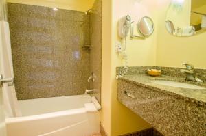 a bathroom with a tub, sink and mirror at Continental Inn in Santa Cruz