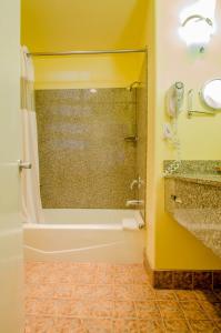 a bathroom with a shower and a tub and a sink at Continental Inn in Santa Cruz