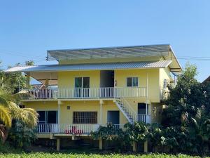 a yellow house with white balconies and palm trees at บ้านตาผ่าน โฮมสเตย์ 