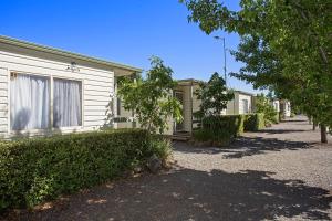 a row of houses with hedges in front of them at Lake Hamilton Motor Village and Caravan Park in Hamilton