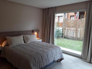 a bedroom with a bed and a large window at Le Cuyen Flat ll in Mar de las Pampas +13 photos