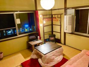 a living room with a table and a couch and windows at Benidaruma - Sakuramochi in Kyoto