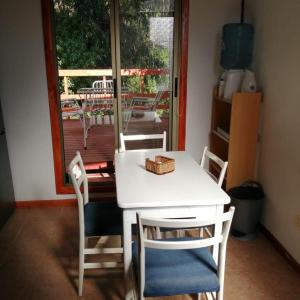 a white table and chairs in a room with a window at CABAÑA ZAPALLAR BOSQUE PLAYA CON HOTTUBE in Zapallar