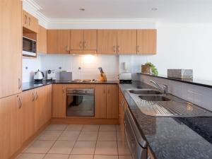 a kitchen with wooden cabinets and black counter tops at Lucys at the Bay in Callala Bay