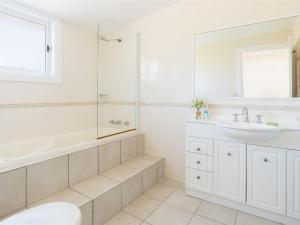 a white bathroom with a tub and a sink at Lucys at the Bay in Callala Bay