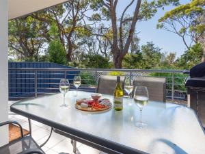a table with two glasses of wine and a plate of food at Lucys at the Bay in Callala Bay
