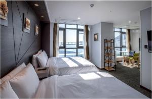 a hotel room with two beds and a balcony at Griffinbay Hotel in Busan