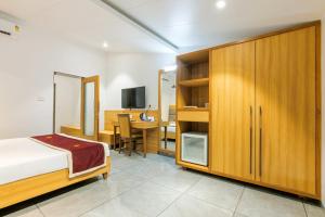 a bedroom with a bed and a desk with a television at Gold Beach Villa in Daman