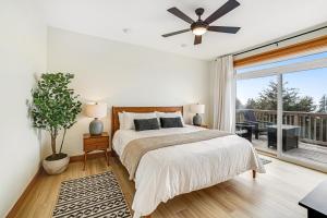 a bedroom with a bed with a ceiling fan and a balcony at Three Capes Bungalow in Oceanside