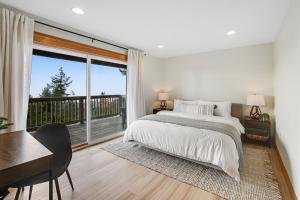 a bedroom with a bed and a desk and a large window at Three Capes Bungalow in Oceanside