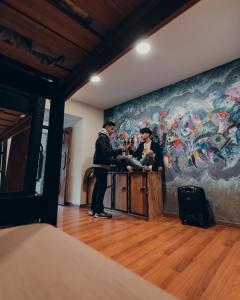 two people standing at a table in a room with a painting at Hommam in Cusco