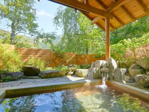 un étang dans un jardin avec un toit en bois dans l'établissement Pension Asanebou, à Minakami