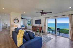 Sala de estar con sofá azul y vistas al océano en Alii Kai Resort #5102, en Princeville