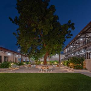 a building with a tree and tables and chairs at Tree of Life Darbargadh Dared in Bhavnagar