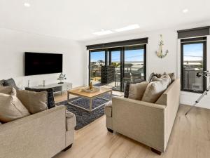 een woonkamer met twee banken en een tv bij Castaway Views in San Remo