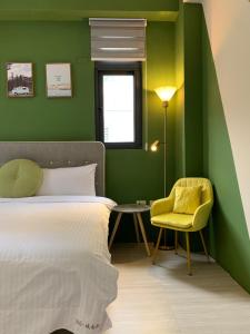 a bedroom with green walls and a bed and a yellow chair at 910 Hostel 城南館-自助入住 in Yuli