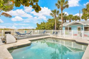 a swimming pool with a white fence and palm trees at Seaside Sweetheart in Clearwater Beach