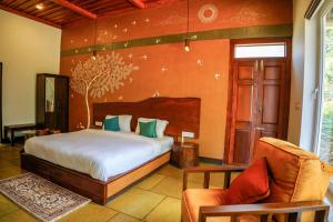 a bedroom with a bed and a couch and a chair at Ananterra Resort Wayanad in Wayanad