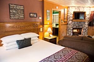 1 dormitorio con cama, sofá y chimenea en Cathy's Cottages en Big Bear Lake