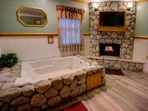 a large bath tub in a room with a stone fireplace at Cathy's Cottages in Big Bear Lake