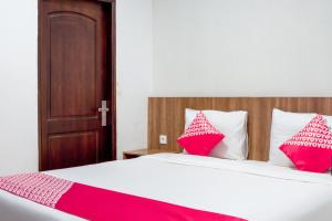 a bedroom with a bed with red and white pillows at Hotel O Papakoel in Medan