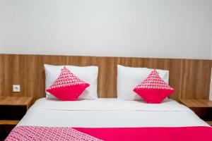 a bedroom with a bed with red and white pillows at Hotel O Papakoel in Medan
