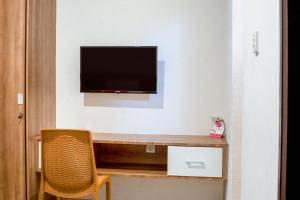a room with a tv on a wall with a chair at Hotel O Papakoel in Medan