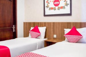 two beds in a room with red and white pillows at Hotel O Papakoel in Medan +20 photos