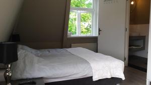 1 dormitorio con 1 cama blanca y ventana en Logies Ommes!, en Harlingen
