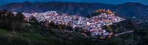 una ciudad en la cima de una montaña por la noche en Hotel Don Pero, en Álora