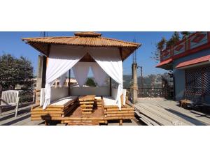 a gazebo with a white canopy on a deck at Mehra Cottage in Almora