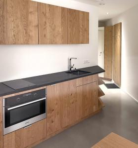 a kitchen with wooden cabinets and a sink at Apartmenthaus Anna mit Self-Check-In und 24h Support in Lustenau