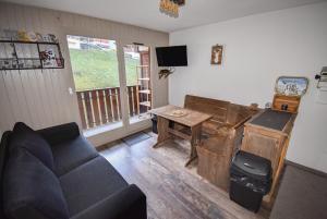 a living room with a couch and a table at Au Pied des Pistes B48, Chaleureux studio 4 pers, balcon plein SUD, DRAPS NON COMPRIS in Saint-Jean-d'Aulps