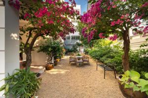 un patio con mesas, sillas y árboles con flores rosas en Hotel Thomas Bangkok, en Makkasan