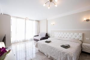 a white bedroom with a bed and a chair at Las Americas de LUX 98m2 in Playa Fañabe