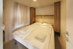 Schlafzimmer mit einem Bett mit weißer Bettwäsche in der Unterkunft Premium Mobile Homes - Hotel & Resort Adria Ankaran in Ankaran