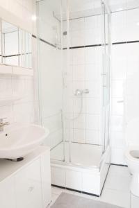 uma casa de banho branca com um chuveiro e um lavatório. em Apartment-EG-05 em Darmstadt