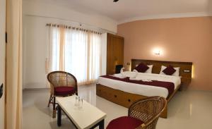 a bedroom with a large bed and a table and chairs at White House Residency in Varkala