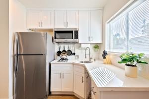 a kitchen with white cabinets and a stainless steel refrigerator at Fair, Sunny, and Blue Weather Days in Newport Beach