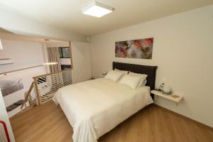 ein Schlafzimmer mit einem weißen Bett und einer Treppe in der Unterkunft City Center Ground Loft - Ioannina in Ioannina