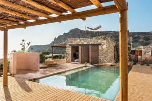 a house with a swimming pool with a mountain in the background at Elafonisi Villas in Livadia