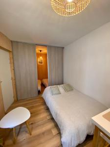 een slaapkamer met een bed, een stoel en een kroonluchter bij N°2 L'épicéa - Appart Hôtel La Maison Sévigné in Béthune