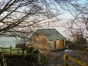una pequeña casa con una puerta amarilla y una valla en Charlottes Cottage, en Bamford