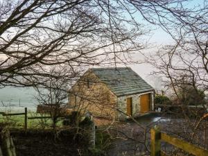 a small house with a yellow door and a fence at Charlottes Cottage in Bamford
